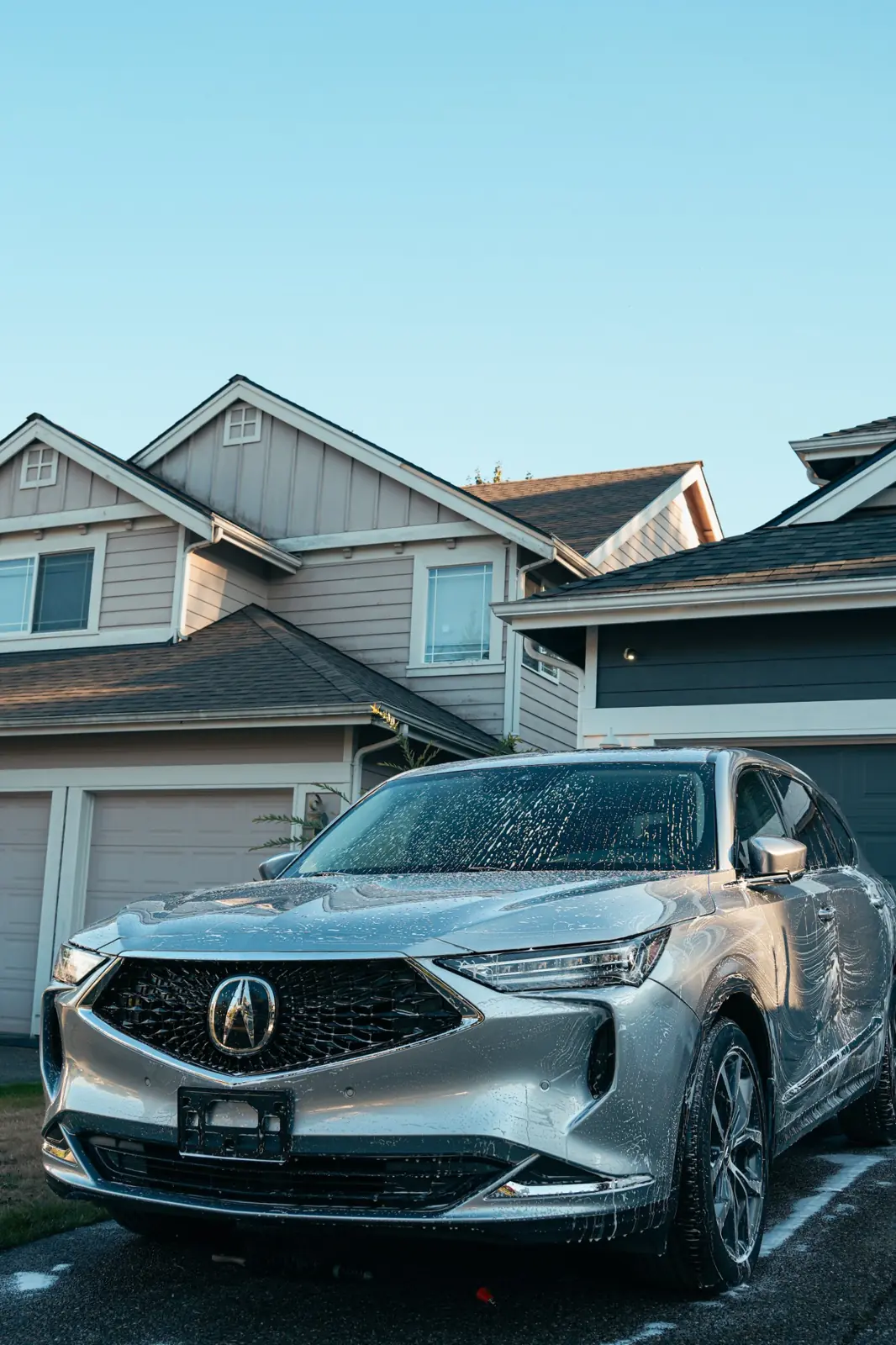 Silver Acura MDX covered in foam in a driveway